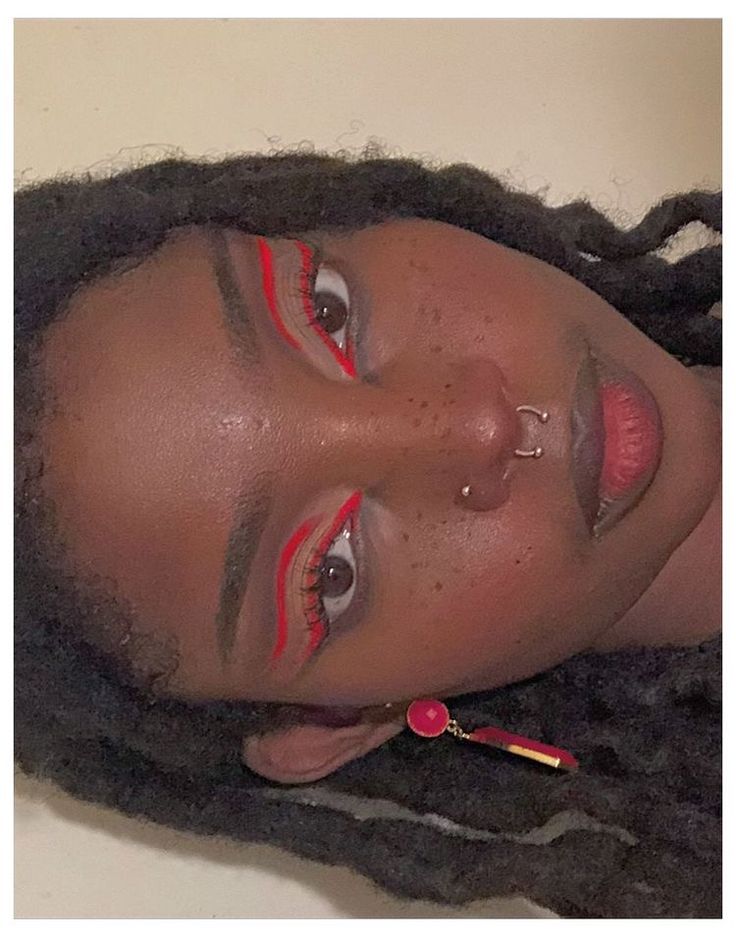 a woman with long dreadlocks and red lipstick on her face is looking at the camera