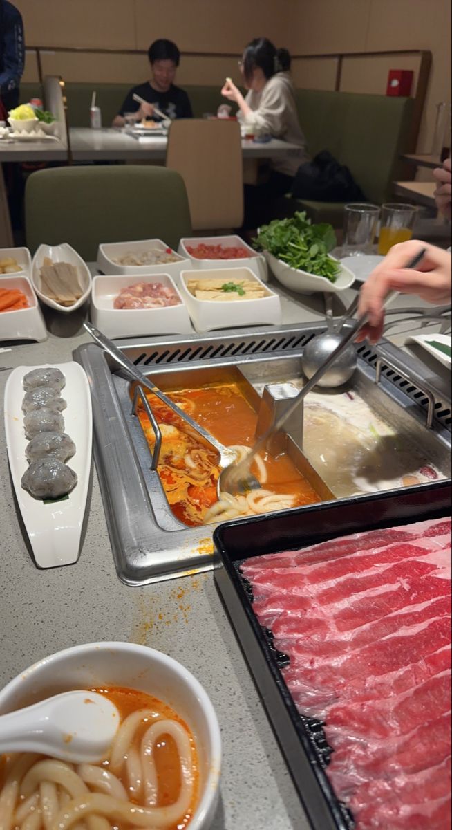 people are preparing food at a buffet table with chopsticks and bowls on it