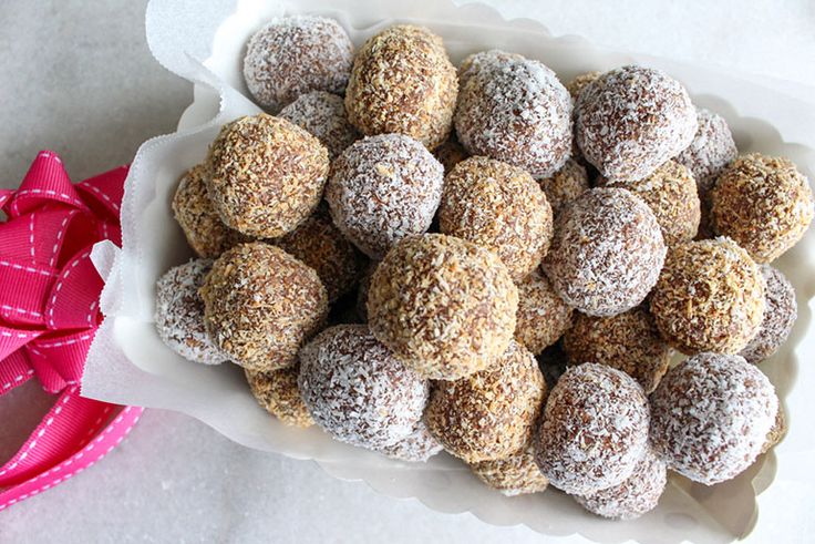 a bowl filled with chocolate covered donuts on top of a table next to a pink bow