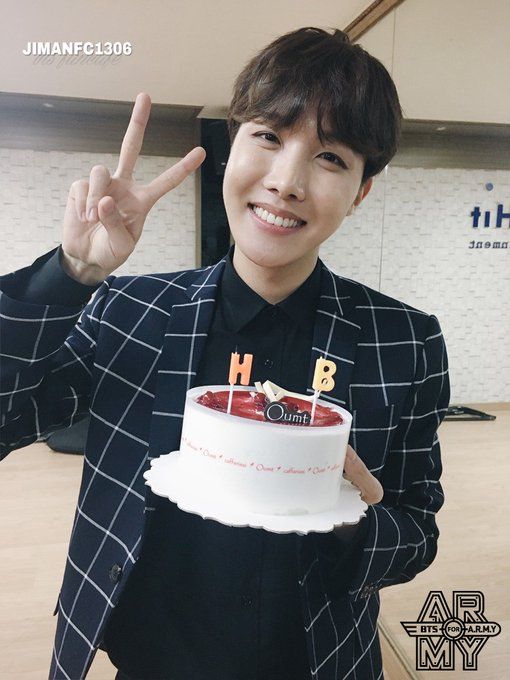 a person holding up a cake with the letter h in front of them and an i sign above it