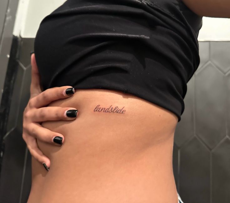 a woman's stomach with the word and date tattooed on it