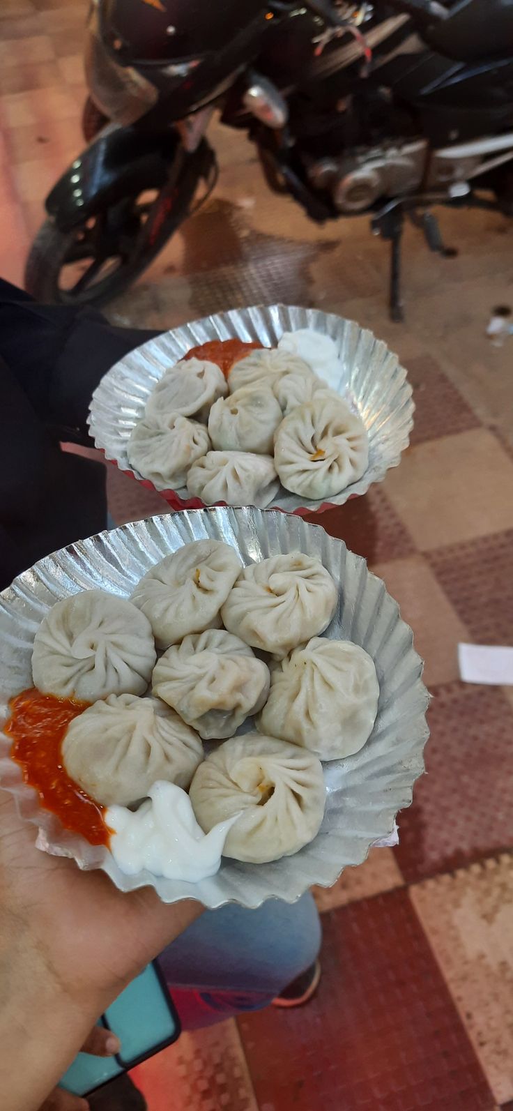 two plates filled with dumplings sitting on top of a table next to a motor scooter