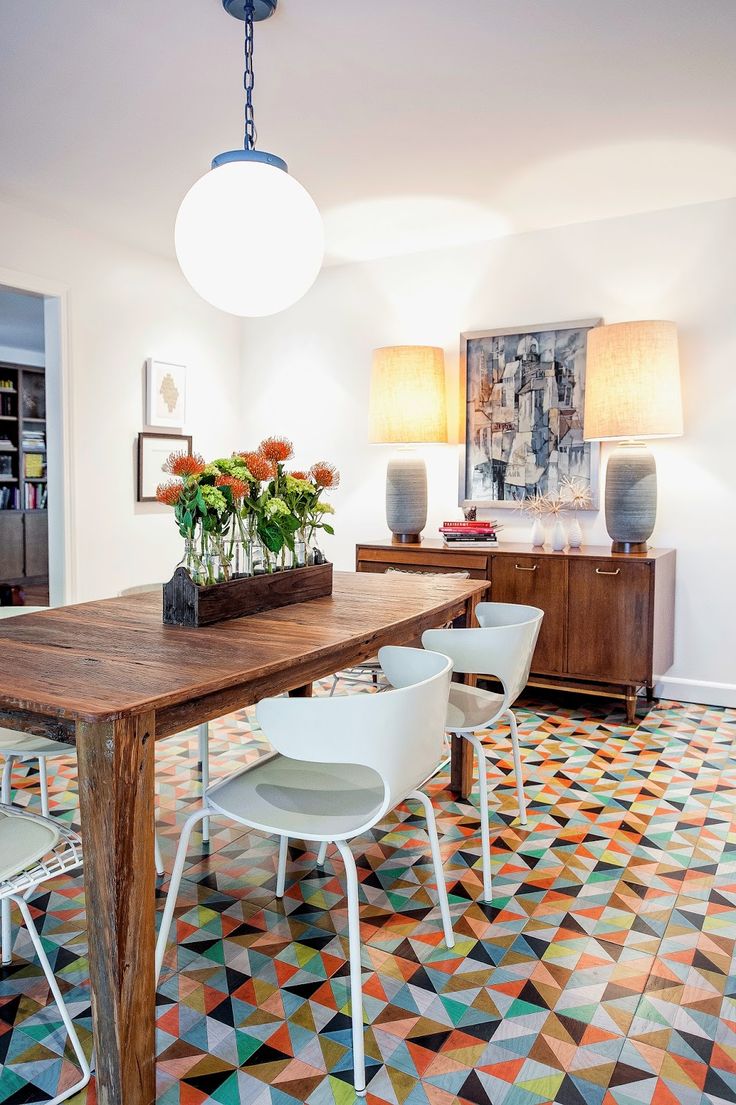 a dining room table with chairs and vases on top of it in front of two lamps