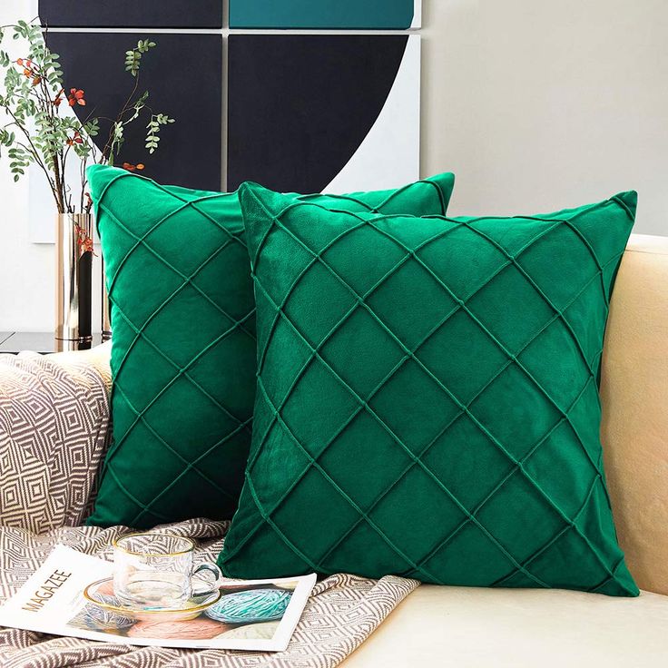 two green pillows sitting on top of a couch next to a vase filled with flowers