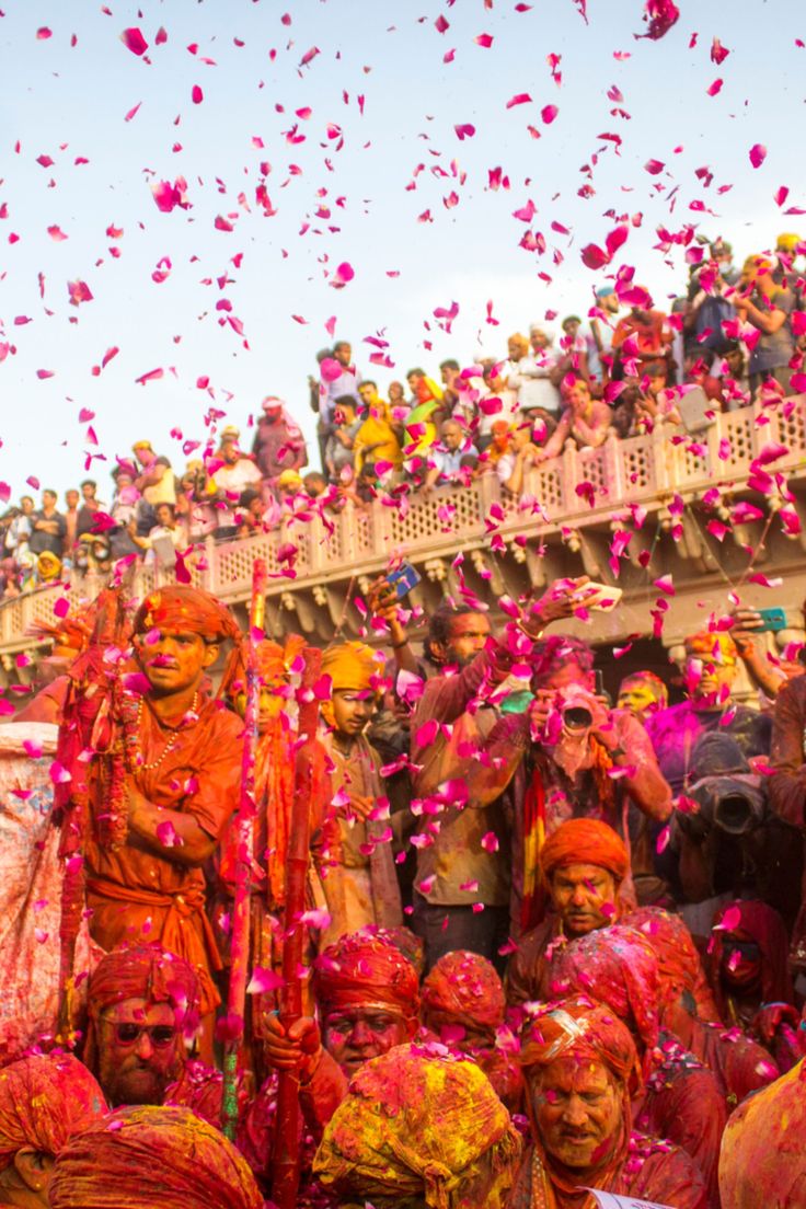 men and women dressed in orange are throwing petals at each other as confetti falls on them