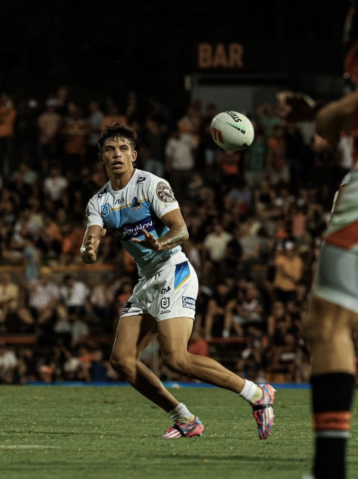 a rugby player is running with the ball in his hand as he prepares to kick it