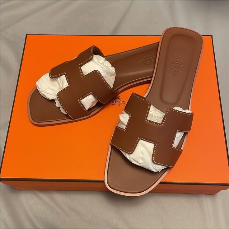 Brand New, Never Worn 100% Authentic Box Leather All Around Hermes Color: Gold ( Dark Camel Tan) Super Popular Classic Color And Hard To Find Perfect To Dress It Up Or Wear It Casually Made In Italy Hermes Fr Size 37.5 (Us 7.5) Luxury Brown Sandals With Round Toe, Luxury Brown Sandals With Leather Lining, Designer Brown Sandals With Leather Lining, Luxury Brown Leather Sandals, Luxury Brown Slip-on Sandals, Designer Brown Leather Sandals, Brown Designer Leather Sandals, Designer Brown Calf Leather Sandals, Designer Brown Open Toe Sandals