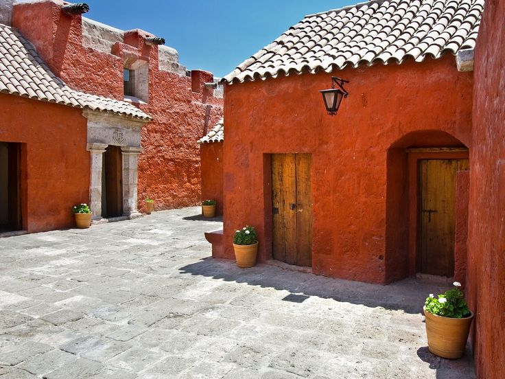 an alley way with potted plants on either side and two doors in the middle