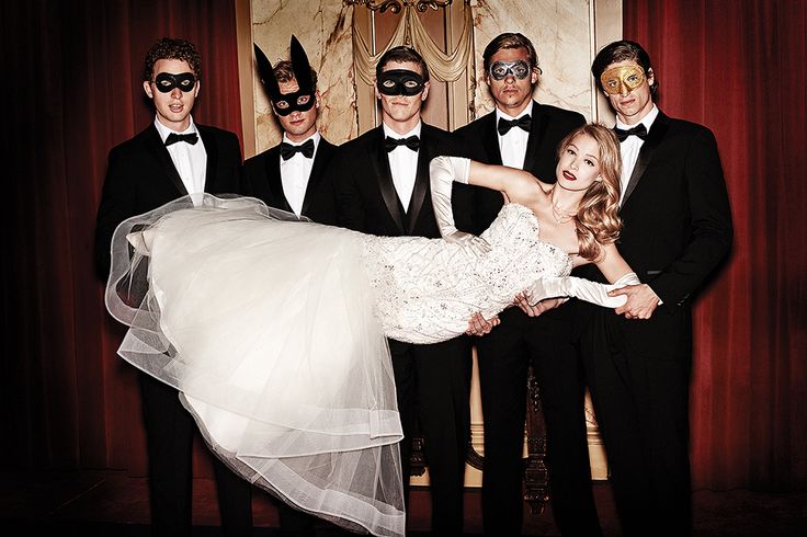 a group of people in tuxedos and masks posing for a photo with a bride