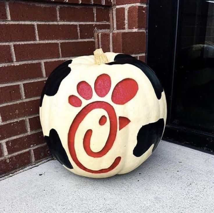 a painted pumpkin sitting on the ground next to a brick wall