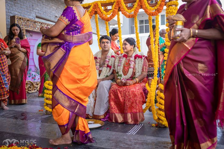 the bride and groom are getting ready for their wedding ceremony to begin, with flower garlands on either side of them