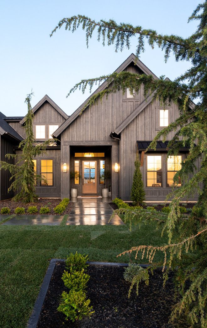 a house that is in the middle of some grass and has lights on it's windows