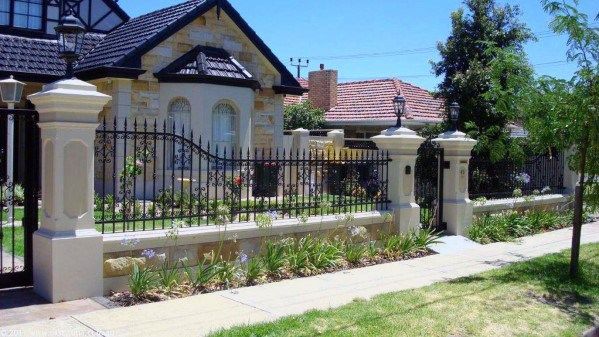 a house that has a fence in front of it and some plants on the side