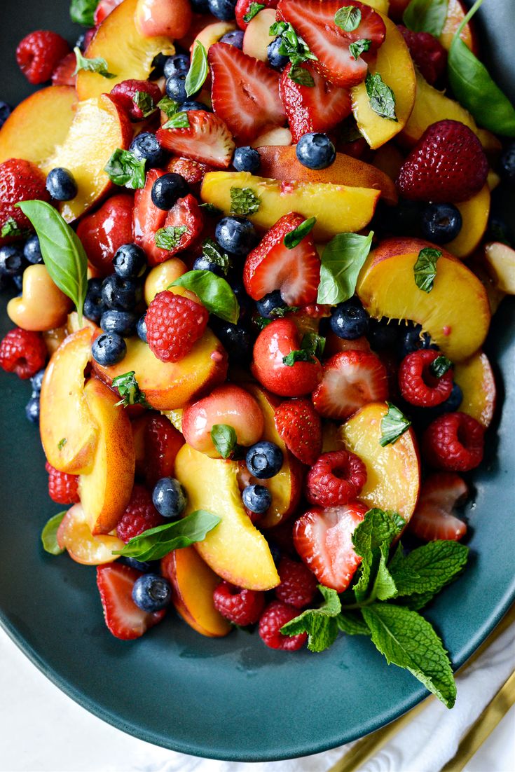 a blue plate topped with fruit salad next to a fork