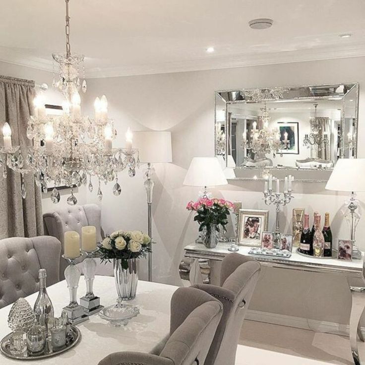 a dining room with chandelier, table and chairs in front of the mirror