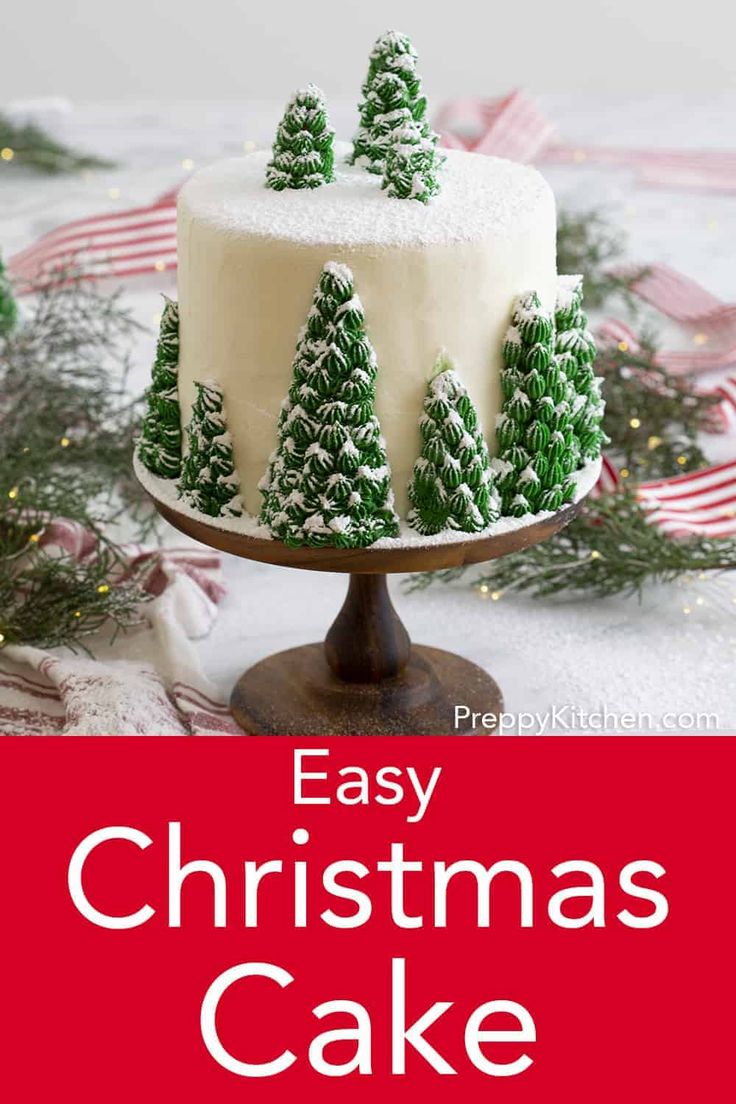 an easy christmas cake with white frosting and green trees on top, sitting on a table