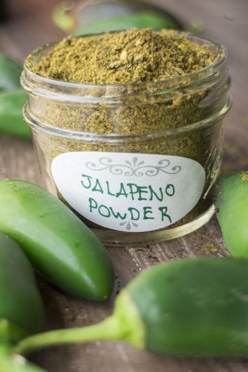 jalapeno powder in a glass jar next to green peppers