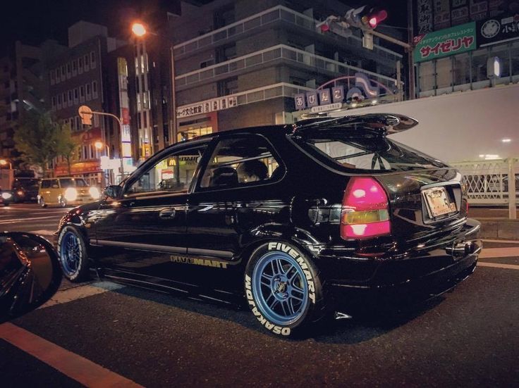 the car is parked on the side of the road near some cars at night time