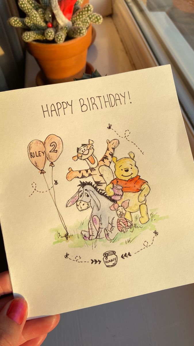 a person holding up a birthday card with winnie the pooh on it