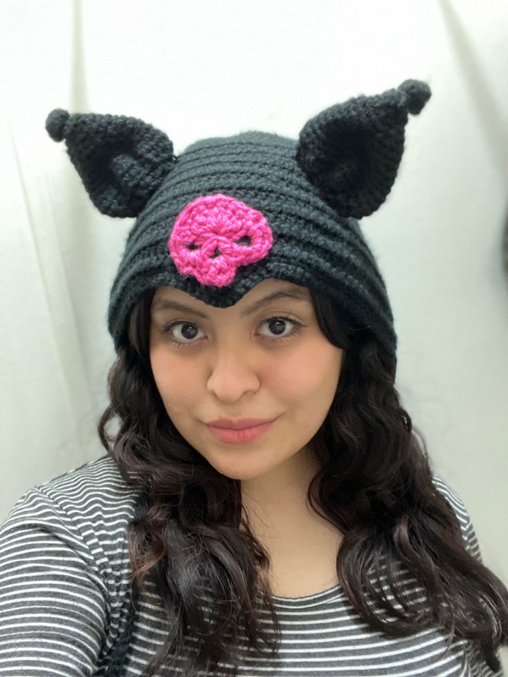 a woman wearing a knitted hat with a pink donut on it's center