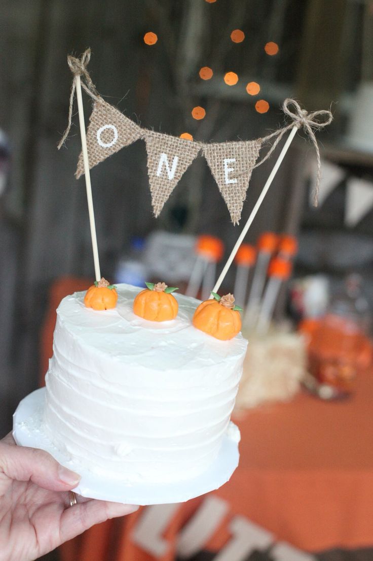 someone is holding up a cake decorated with oranges and bunting on the top