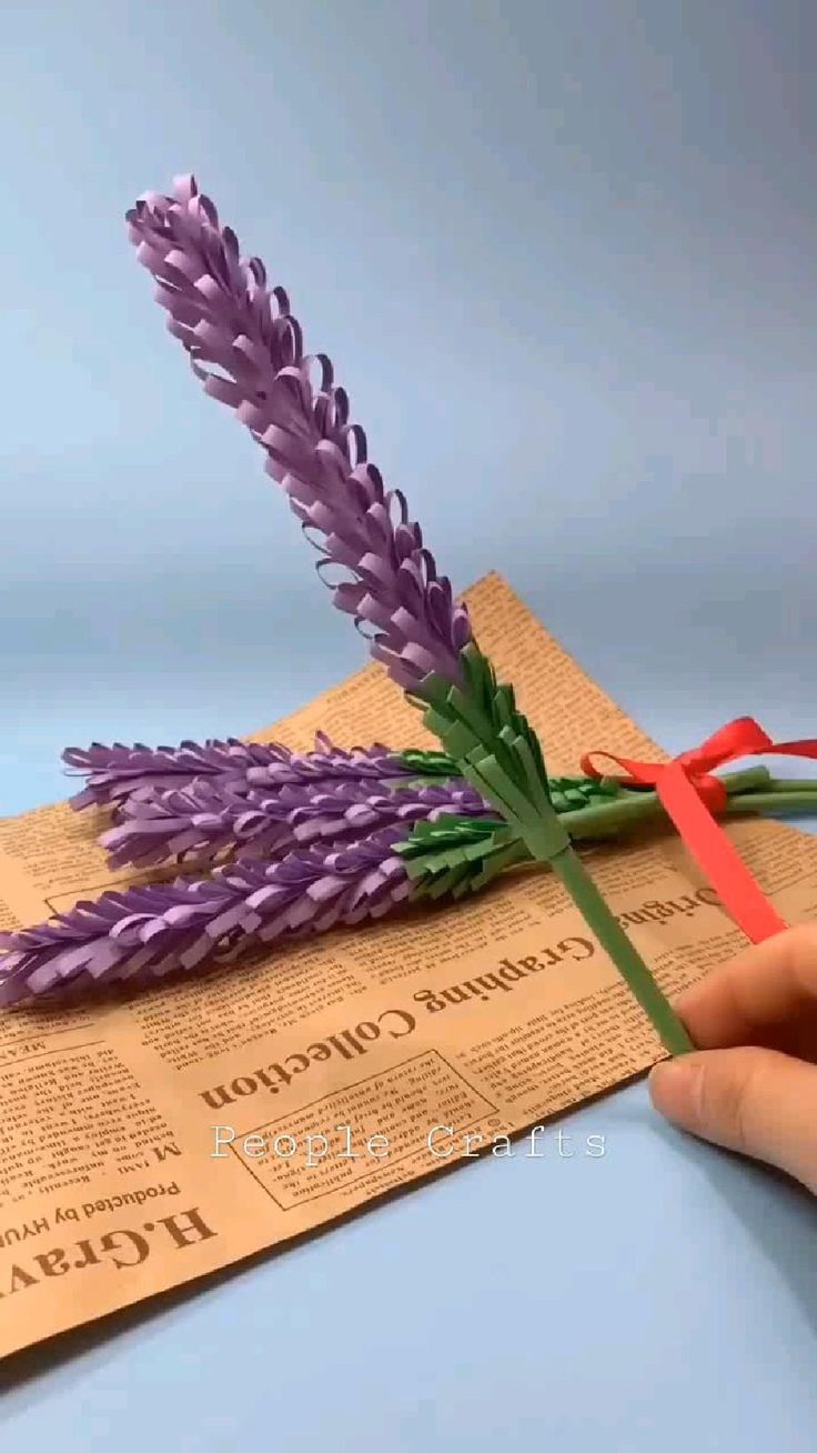 a person is cutting paper with scissors to make it look like they are holding flowers