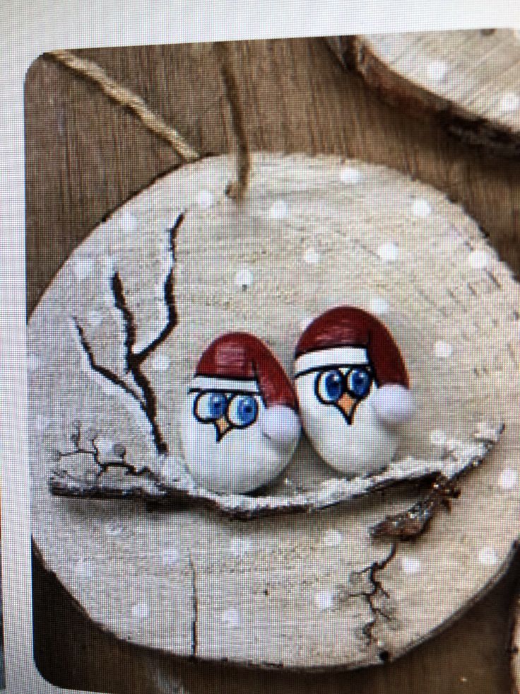 two red and white birds sitting on top of a piece of wood with eyes painted on it