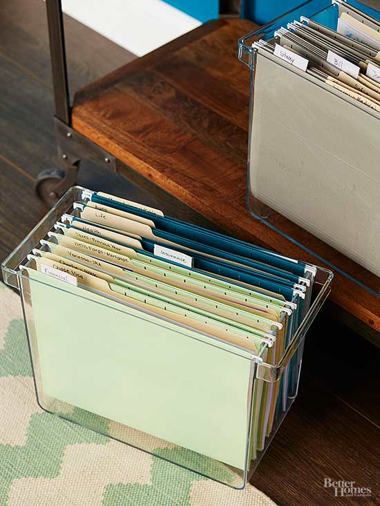 a stack of file folders sitting on top of a wooden table next to a drawer