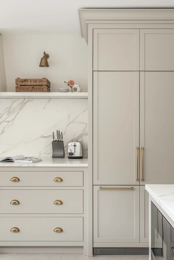 a kitchen with white cabinets and marble counter tops