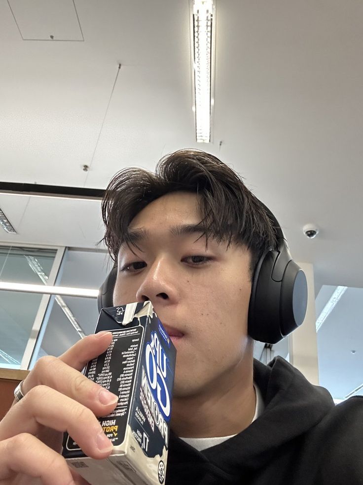 a young man wearing headphones and eating an ice cream bar in front of his face