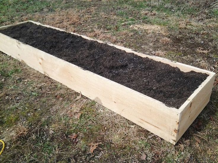 a wooden box filled with dirt on top of grass