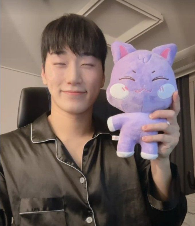 a man holding up a purple cat stuffed animal