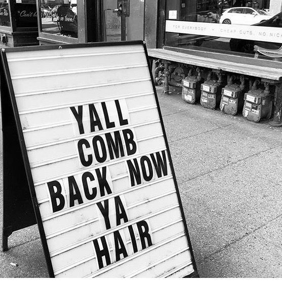 a black and white photo of a sign that says yal comb back now ya hair