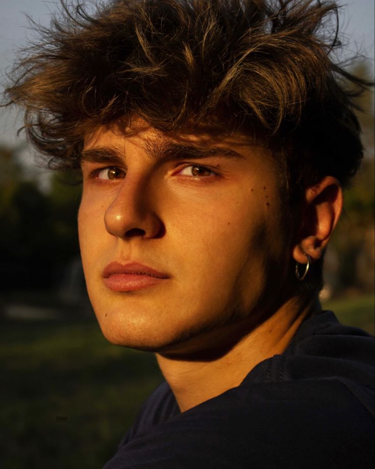 a young man with his hair blowing in the wind and looking off into the distance