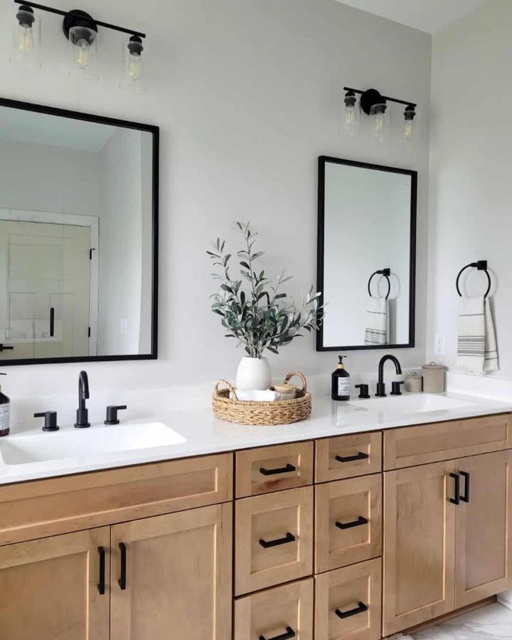 In a gray modern bathroom, a natural double vanity and a white countertop is decorated with a flat bottom, round woven seagrass basket. It holds a round white vase of greenery, a glass jar with a wooden lid, and a rolled towel. Bathroom Double Sink Ideas, Modern Bathroom With Wood, Bathroom With Wood Vanity, Sink Bathroom Ideas, Gray Modern Bathroom, Double Vanity Bathroom Ideas, Double Sink Bathroom Ideas, Vanity Bathroom Ideas, Bathroom Double Sink