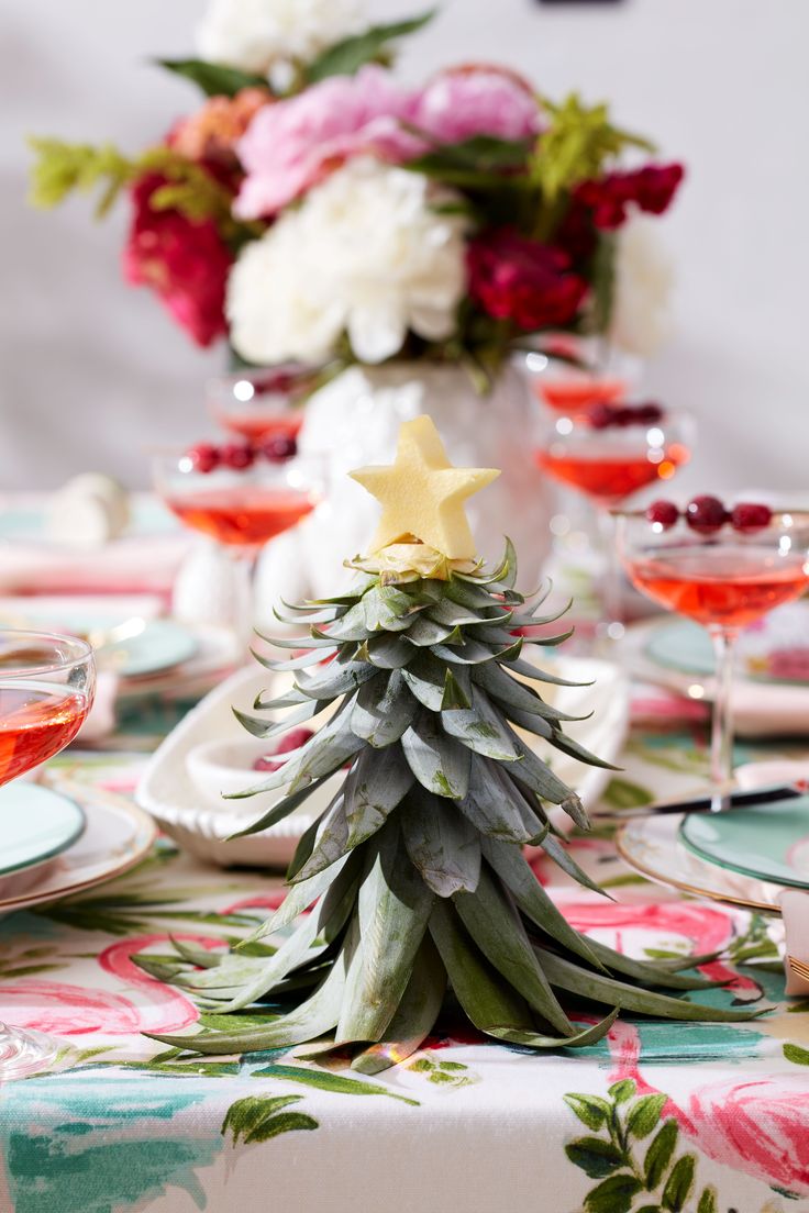 a table topped with plates and glasses filled with drinks next to a small christmas tree