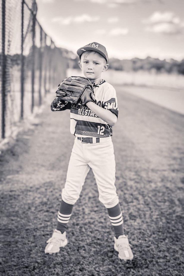 a young baseball player standing in the dirt with his mitt up to his chest