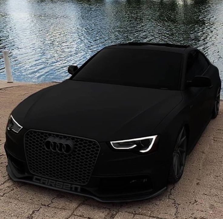 a black car parked next to a body of water