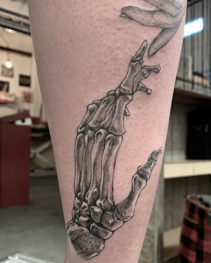 a person with a tattoo on their leg that has a skeleton in the shape of a hand