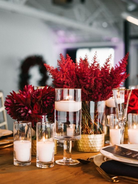 a table set with candles and flowers in vases on top of it, surrounded by other place settings