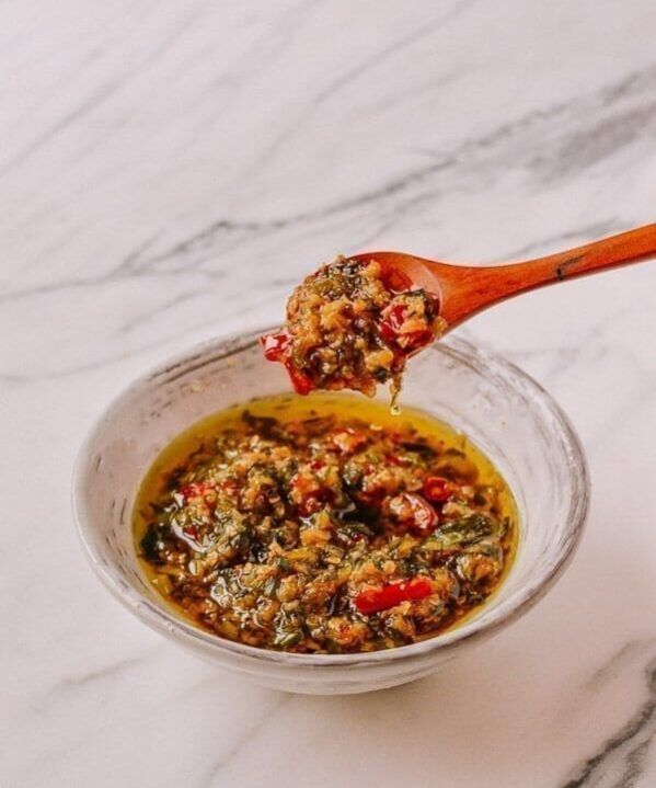 a spoon full of food sitting on top of a white marble counter next to a bowl