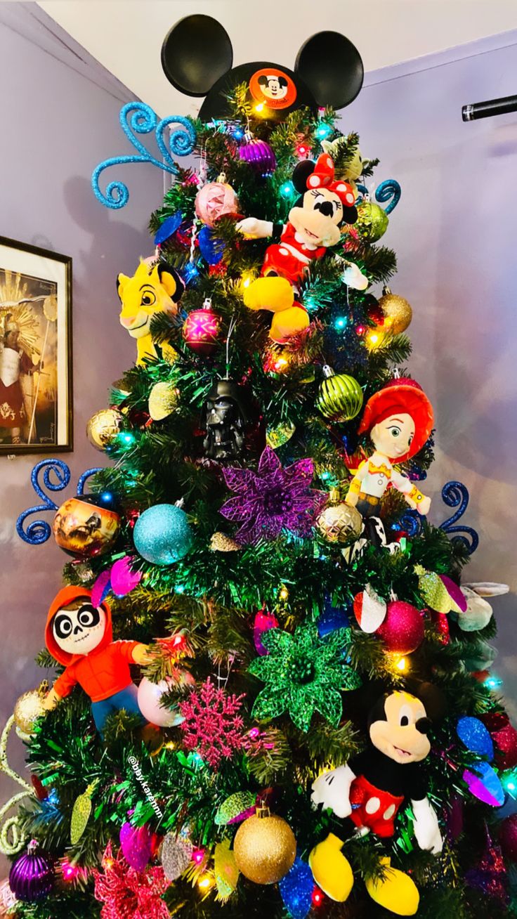 a christmas tree with mickey mouse decorations and other disney character ornaments on it's top