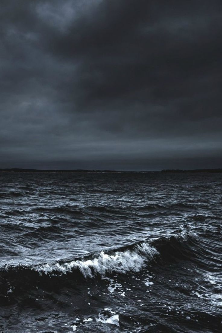 an ocean with waves and dark clouds in the sky