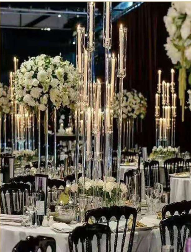 the tables are set with black chairs and white flowers in tall vases on them