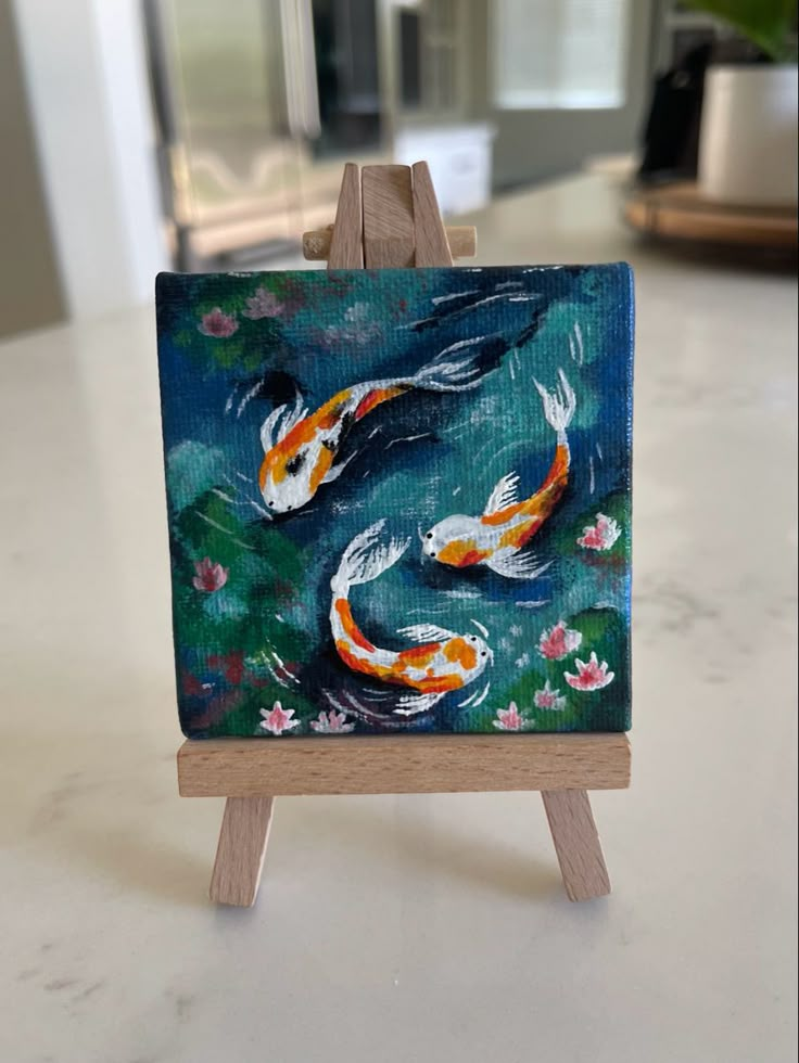 an easel with a painting of two koi fish on it's side