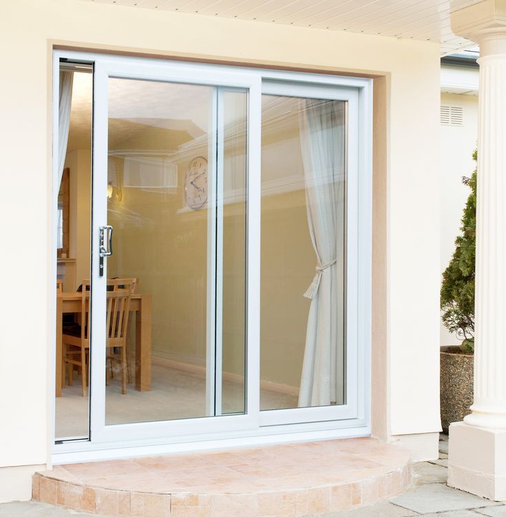 an open sliding glass door in front of a dining room table and chairs outside the house