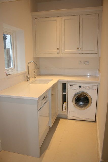 a washer and dryer are in the corner of a kitchen with white cabinets