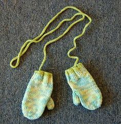 two green mittens hanging from a string on the floor