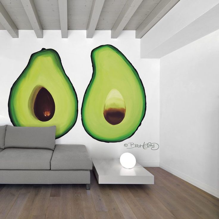 an avocado mural on the wall behind a couch in a room with wood floors