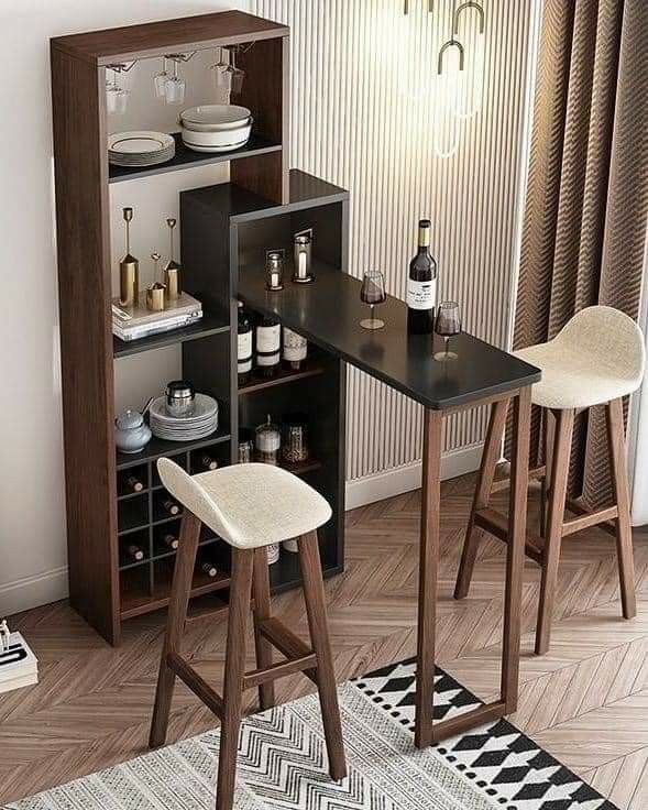 a small table with two stools in front of it next to a shelf filled with bottles